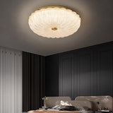 "A modern glass ceiling light with a brass frame, mounted on a ceiling in a contemporary bedroom."