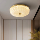 "A modern glass ceiling light with a brass frame, casting a warm glow on a white ceiling."