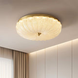 "A modern ceiling light with a brass frame and glass shade, mounted on a white ceiling."