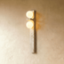 "Two modern travertine wall lamps with two frosted glass globes each, mounted on a wall on either side of a sofa in a living room."