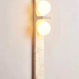 "A modern travertine wall sconce with two spherical white glass shades mounted on a vertical travertine base."
