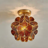 "A close-up of an amber, floral-inspired ceiling light with a brass frame and textured glass petals, showcasing its intricate details and warm glow."