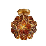 "A warm amber ceiling light with a brass frame and intricately patterned glass petals, creating a rich and inviting ambiance."
