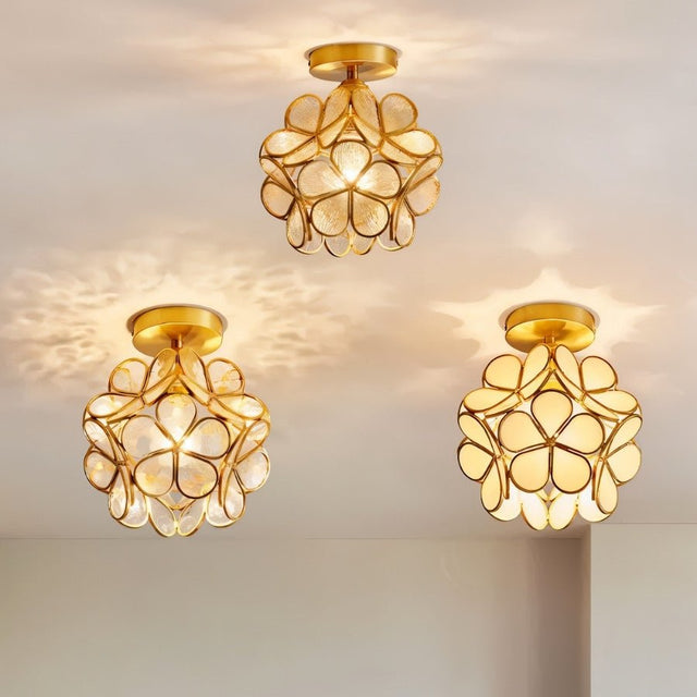 "Three floral-inspired ceiling lights with brass frames and luminous glass petals, installed in a row to create a visually striking effect."