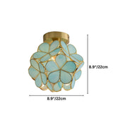"A floral-inspired ceiling light with a brass frame and delicate, light blue glass petals, emitting a warm glow."