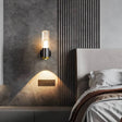 "Modern cylindrical wall lamp with a metal base and acrylic diffuser providing accent lighting in a contemporary bedroom."