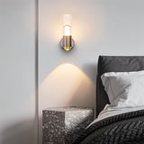 "Modern cylindrical wall lamp with a metal base and acrylic diffuser providing ambient light in a bedroom."
