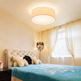 "Contemporary bedroom featuring a minimalist fabric drum ceiling light providing soft, ambient illumination."