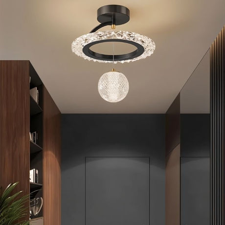 "A black ceiling light with a circular frame and a hanging crystal sphere, installed in a hallway with a dark gray door and dark wood paneling."