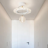 "A white ceiling light with a circular frame and a hanging crystal sphere, installed in a white hallway."