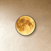 Round moon-shaped wall light with warm glow in modern living room with dark furniture and textured gray walls.