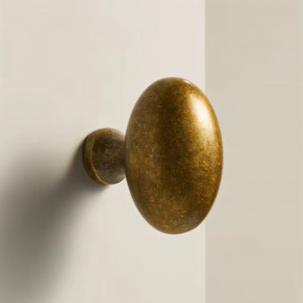 "Close-up of an oval antique brass knob, showcasing its smooth, ergonomic grip and suitable design for cabinets, drawers, and doors."