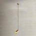 Gold pendant light with adjustable angle hanging from ceiling rod against white wall.
