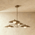 Multi-tier saucer pendant light with brushed brass finish, three suspended shades, white studio background, front view.