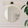 "Modern bathroom vanity light with gold accents and a linear design above a round mirror."