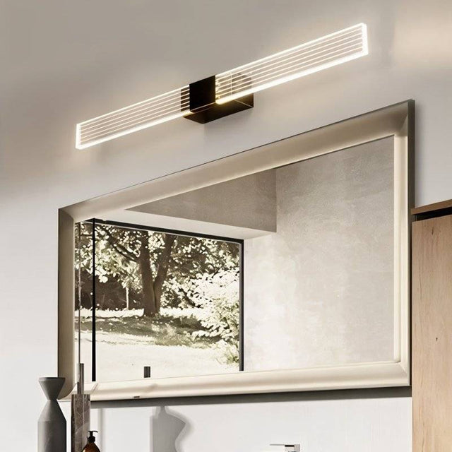 "Black metal and acrylic wall lamp with linear slats, mounted above a rectangular bathroom mirror."