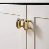 "Pair of sleek, capsule-shaped brass knobs on modern white cabinets."