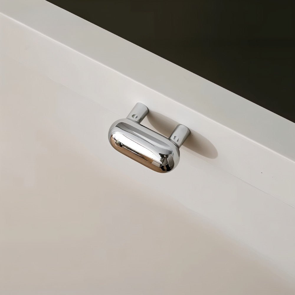 "Sleek, capsule-shaped chrome knob on a modern white drawer."