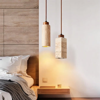 "Modern minimalist pendant lights with cylindrical and rectangular travertine bodies, adding a touch of rustic charm to a contemporary bedroom."