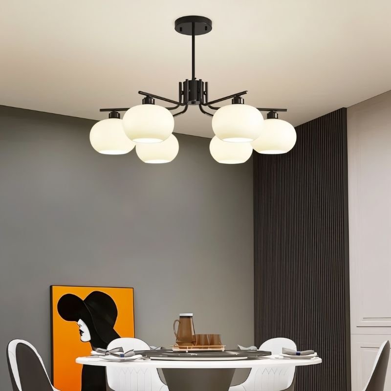 "A 6-light round chandelier with opal glass globes and a black metal frame, hanging above a dining table in a modern dining room."