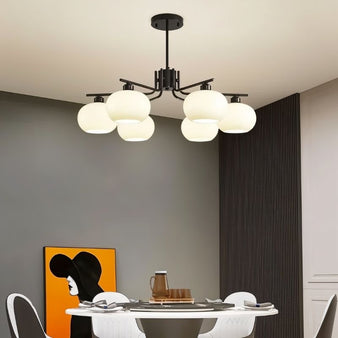 "A 6-light round chandelier with opal glass globes and a black metal frame, hanging above a dining table in a modern dining room."