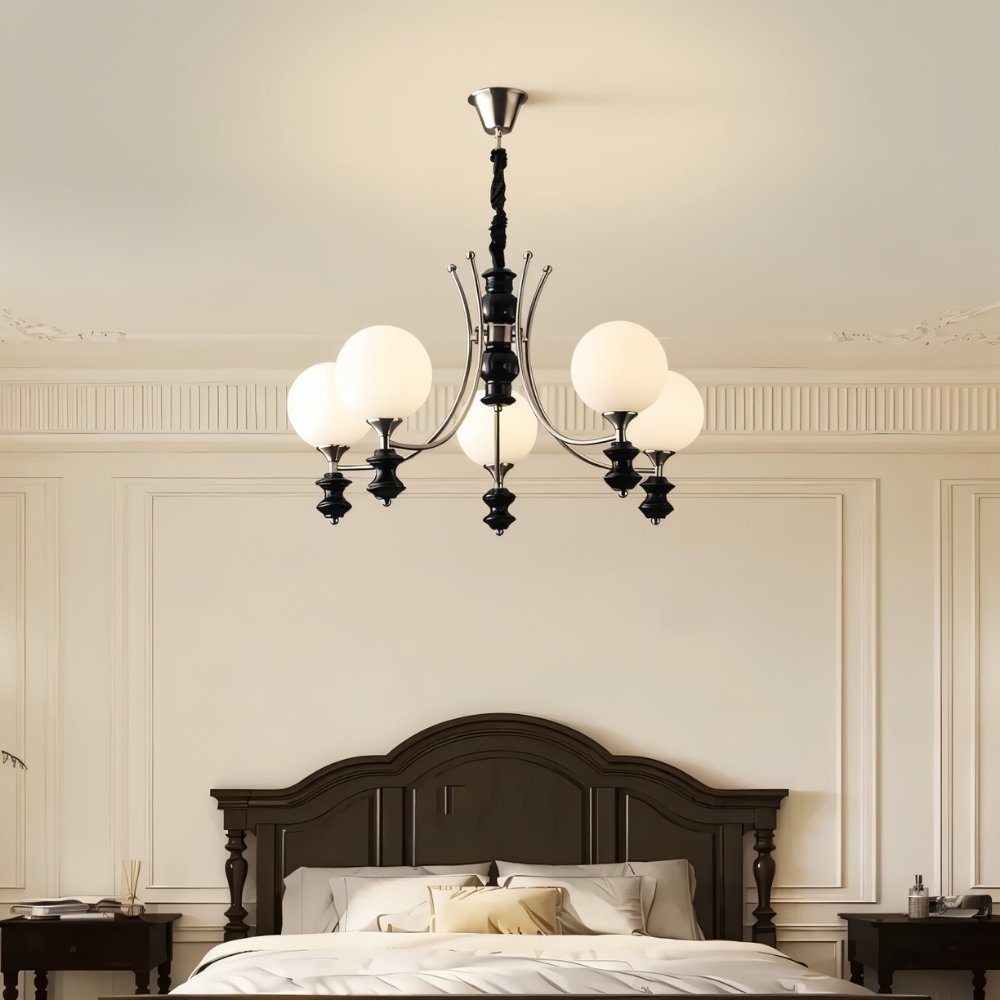  "Modern chandelier with curved arms and frosted glass globes providing ambient light in a bedroom."