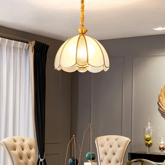 "A vintage-style pendant light with a scalloped glass shade and copper frame hanging in an elegantly decorated room."