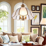 "A vintage-style pendant light with a scalloped glass shade and copper frame hanging in a cozy living room."