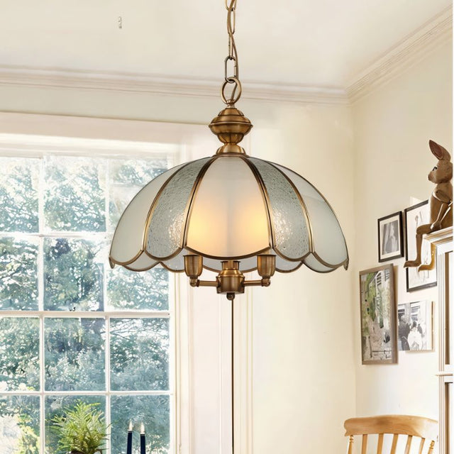 "A vintage-style pendant light with a scalloped glass shade and copper frame hanging in a bright, vintage-styled room."