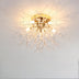 Gold flush mount ceiling light with crystal strands radiating from central fixture against white ceiling.