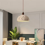 "Wabi Sabi cement pendant light with a minimalist shape and industrial finish, hanging over a rectangular dining table in a contemporary dining room."