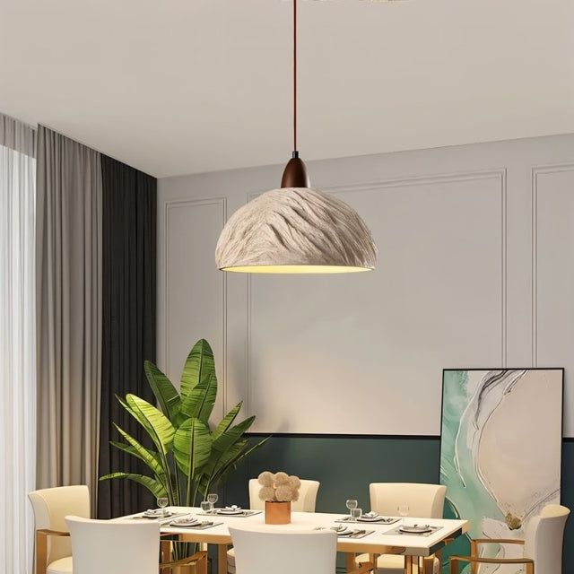 "Wabi Sabi cement pendant light with a minimalist shape and industrial finish, hanging over a rectangular dining table in a contemporary dining room."
