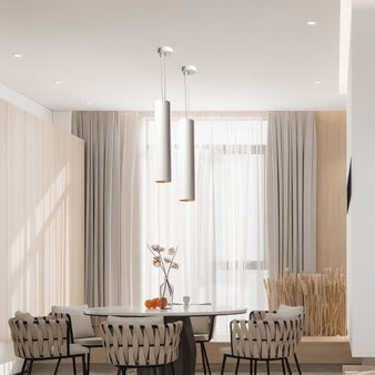 White aluminum Benni Pendant Lights in a contemporary dining area with a round table, woven chairs, and soft natural lighting.