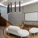 Black aluminum Benni Pendant Lights in a modern living room with a white sofa, wooden flooring, and a home theater setup.