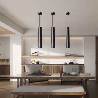 Sleek black aluminum Benni Pendant Light in a modern dining room, featuring three cylindrical lights above a wooden table with neutral decor.