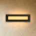 Recessed rectangular wall light with white trim in dark frame, illuminated yellow, mounted on gray wall in modern interior ha
