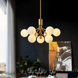 "A gold chandelier with glass balls over a dining table with glasses."