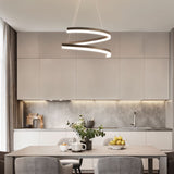 "Modern pendant light with a spiral ribbon design over a dining table in a contemporary kitchen with gray cabinets."