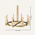 Round brass chandelier with amber glass cylinders and vertical brass rods on cream background.