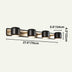 Four-light black cylindrical vanity fixture with brass accents mounted horizontally on cream background.