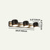 Three-light matte black cylindrical vanity lamp with brushed brass accents on a beige background.