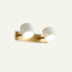 Two-light wall lamp with brass base and white cylindrical shades on neutral background.