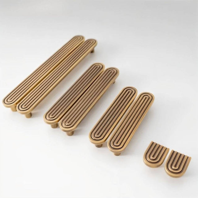 "Set of brass Art Deco knobs and pulls with rounded edges and parallel lines."