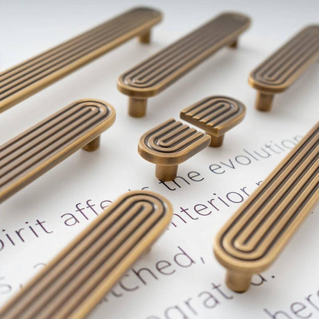 "Brass Art Deco knobs and pulls with rounded edges and parallel lines."
