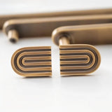 "Pair of brass Art Deco knobs with rounded edges and parallel lines."