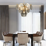 "A modern chandelier with layered smoked glass discs hanging above a dining table in a contemporary dining room."