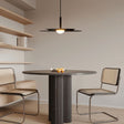 "A disc-shaped pendant light hanging above a round dining table with two chairs."