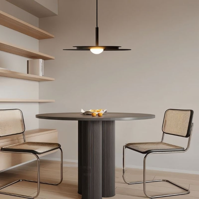 "A disc-shaped pendant light hanging above a round dining table with two chairs."