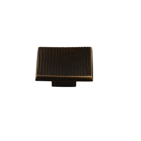 "Studio shot of a single bronze square cabinet knob with a ridged, textured surface on a white background."