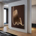 Illuminated brush stroke wall art with warm gold lighting on dark brown canvas in modern interior space.